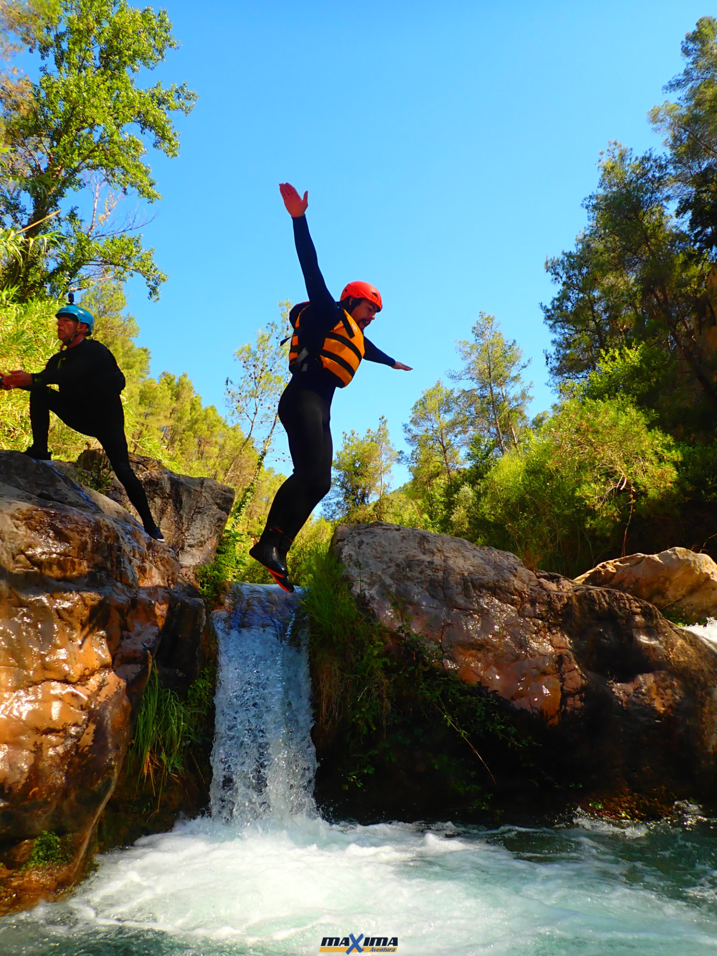 Participante saltando por una cascada en una actividad de barranquismo